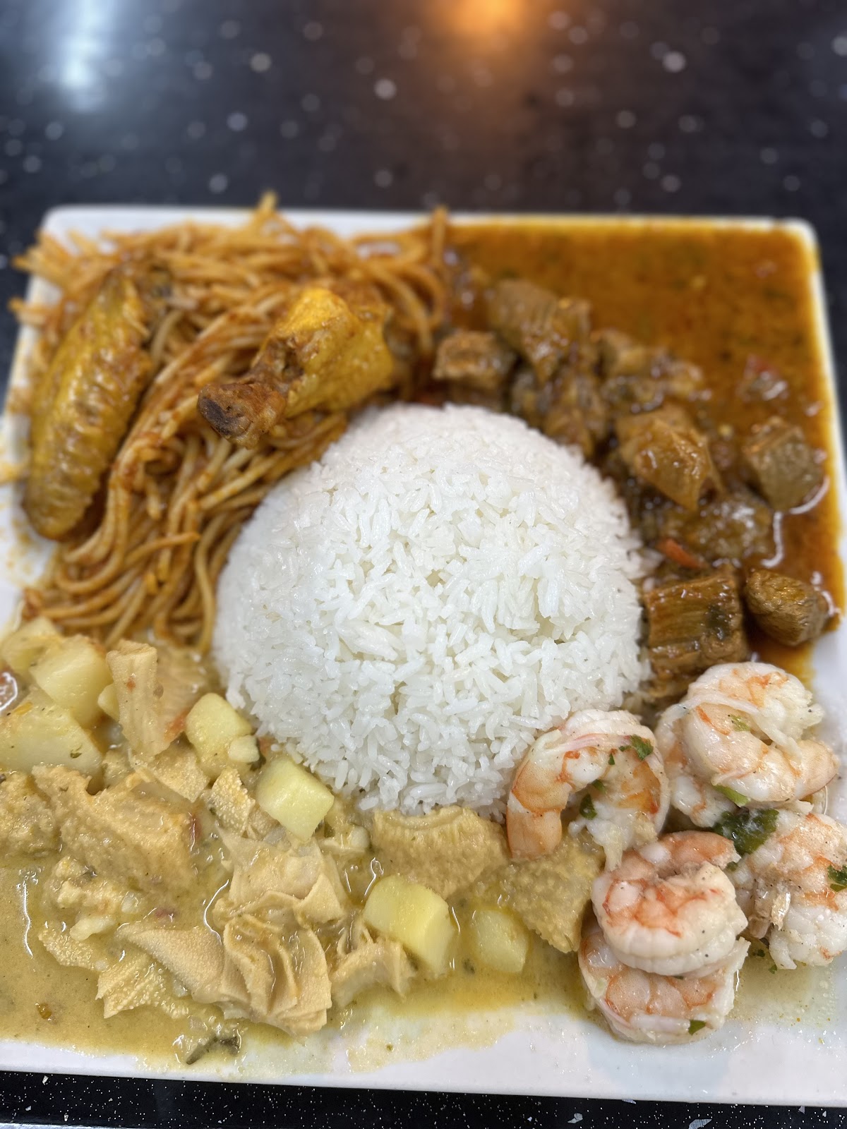 Plato variado con arroz, pollo, fideos, carne y camarones en salsa